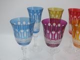 several different colored glass goblets are lined up on a white surface