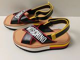 une paire de sandales Moschino noires et jaunes posées sur une surface blanche