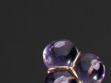 un gros plan d'une bague ornée de deux pierres violettes sur un fond noir