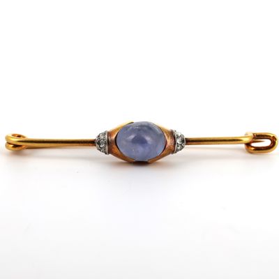 une image représentant une broche en or et en pierre bleue sur fond blanc