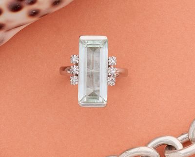 une bague sertie d'une aigue-marine et de diamants sur un fond de corail
