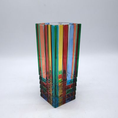 vase en verre multicolore posé sur une surface blanche, sur fond blanc