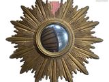 a gold starburst mirror hanging on the wall