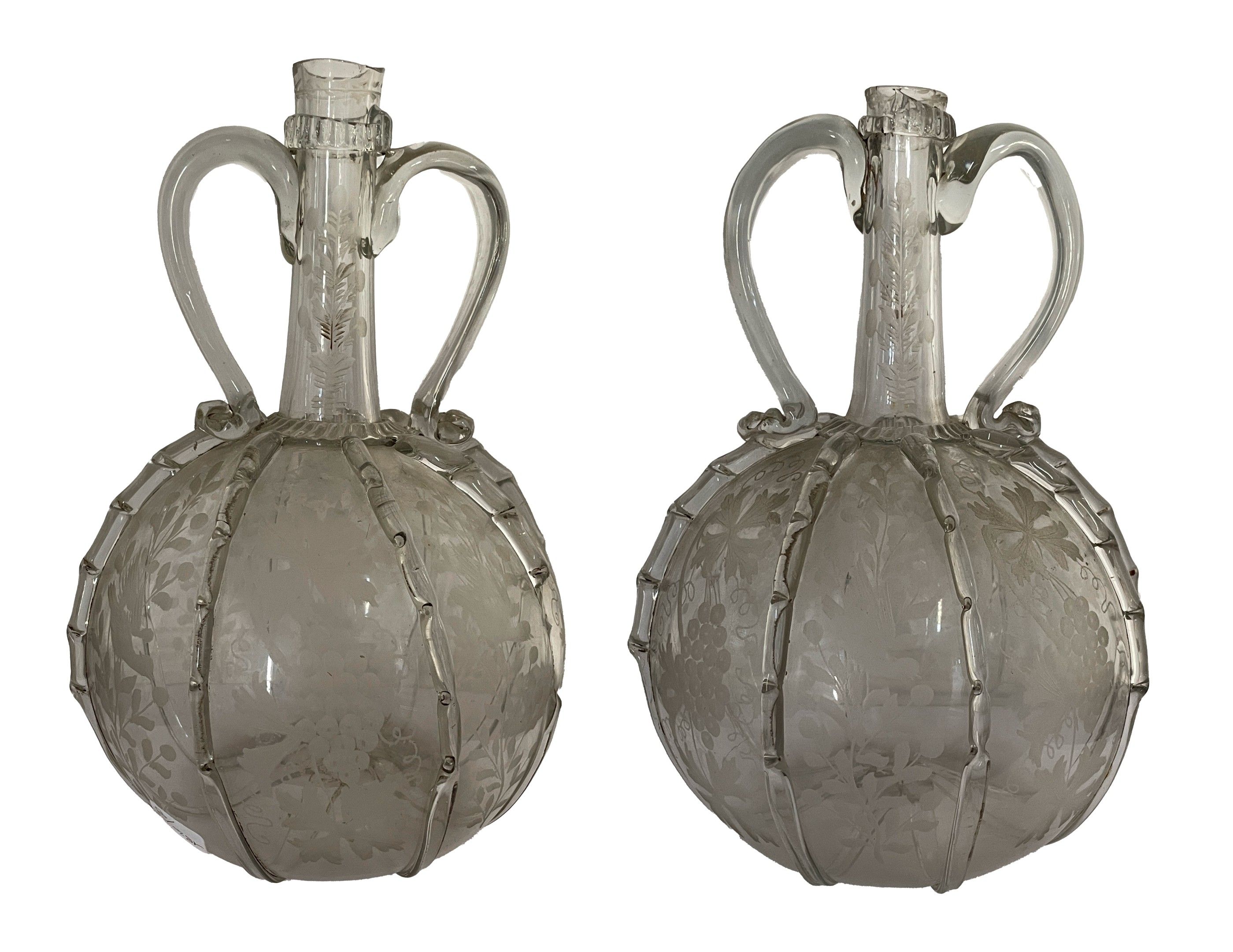 Paire de carafes en verre soufflé, de forme globulaire à col resserré et deux anses en volutes à décor gravé alterné ...
