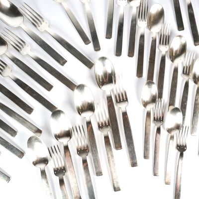 de nombreuses fourchettes et cuillères disposées sur une surface blanche