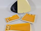 a set of four yellow and black dishes with a black and white plate