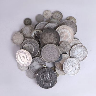 un tas d'argent et de pièces d'argent posé sur une surface blanche