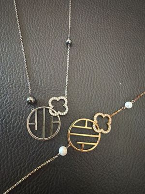 two gold and silver necklaces on a black leather surface