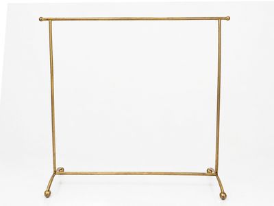 un portemanteau en métal doré à trois pieds et muni d'une seule tringle