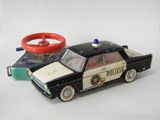 une petite voiture et un volant jouets posés sur une surface blanche