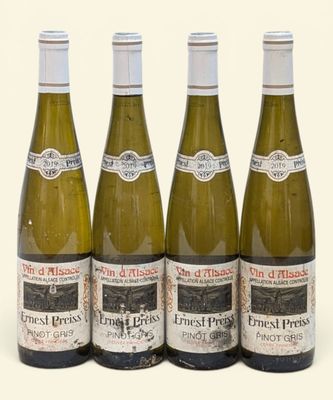 quatre bouteilles de vin sont alignées sur une surface blanche