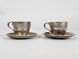 a pair of silver cups and saucers on a saucer