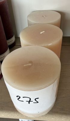 Plusieurs bougies sont alignées sur une étagère, à côté d'une bouteille de vin