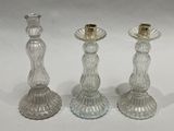 three clear glass candlesticks with gold rims on a white surface
