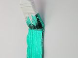 a white paint brush with green paint on a white surface