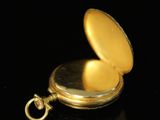 a close up of a gold pocket watch on a black surface