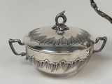 a silver bowl with a handle and a spoon on it