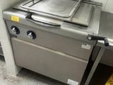 une cuisinière sur laquelle est posée une casserole, dans une cuisine