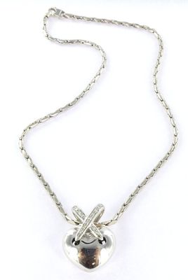 a close up of a silver necklace with a heart on it
