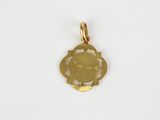 a small gold pendant with a face on it