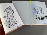 two open notebooks with drawings of a woman and a man on them