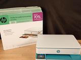 a white and blue printer sitting on a table next to a box