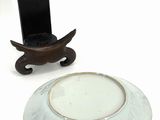 a white plate with a bird on it next to a cell phone