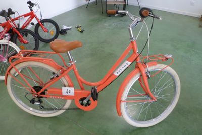 un vélo orange garé dans une pièce avec d'autres vélos
