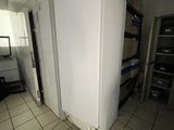 a white refrigerator in the middle of a room with a lot of clutter