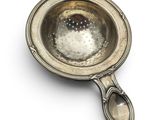 a metal strainer with a spoon in it on a white surface