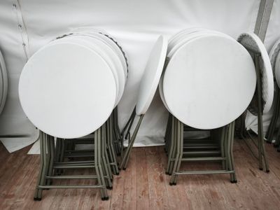trois chaises pliantes blanches placées les unes à côté des autres sur un parquet