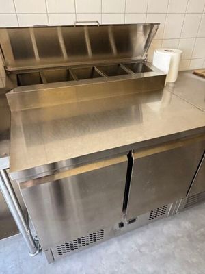 a stainless steel counter with two sinks and a roll of toilet paper on it