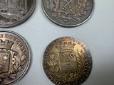 four different coins are shown on a white surface with a white background