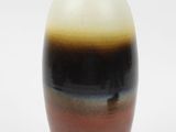 un vase brun et noir posé sur une surface blanche