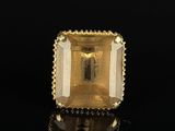 a gold ring with an emerald stone on a black surface