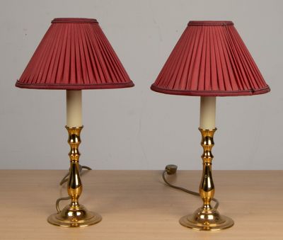 une paire de lampes rouges posées sur une table en bois, avec un mur blanc en arrière-plan