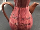 a red coffee pot with writing on it sitting on a table