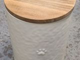 a white canister with a wooden lid on a concrete floor