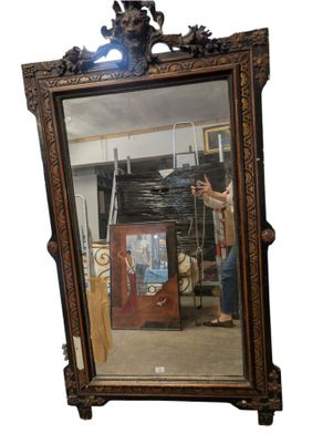 un grand miroir devant lequel se tient un homme