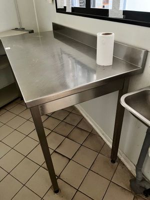 une table en acier inoxydable sur laquelle se trouve une poubelle