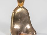 une image représentant une figurine en or posée sur une surface blanche
