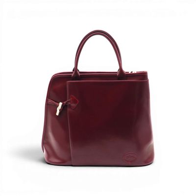 the burgundy leather handbag is sitting on a white surface
