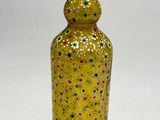 une bouteille en verre jaune ornée de pois multicolores