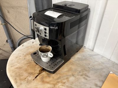 a coffee maker sitting on a table with a cup of coffee