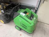 une machine verte garée au sol à côté d'un garage