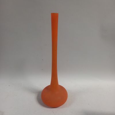 un vase orange posé sur une surface blanche