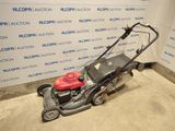a red lawn mower sitting on the ground in front of a wall