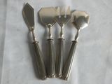 four silver plated serving utensils on a white cloth
