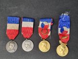 four medals are shown on a black surface with a red, white, and blue ribbon