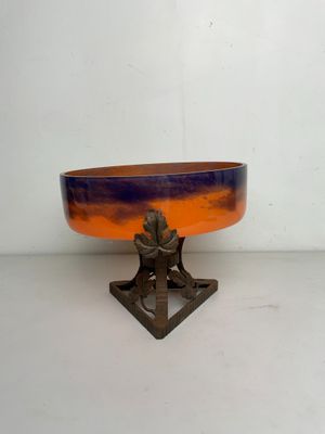 un bol orange et bleu posé sur un socle en métal